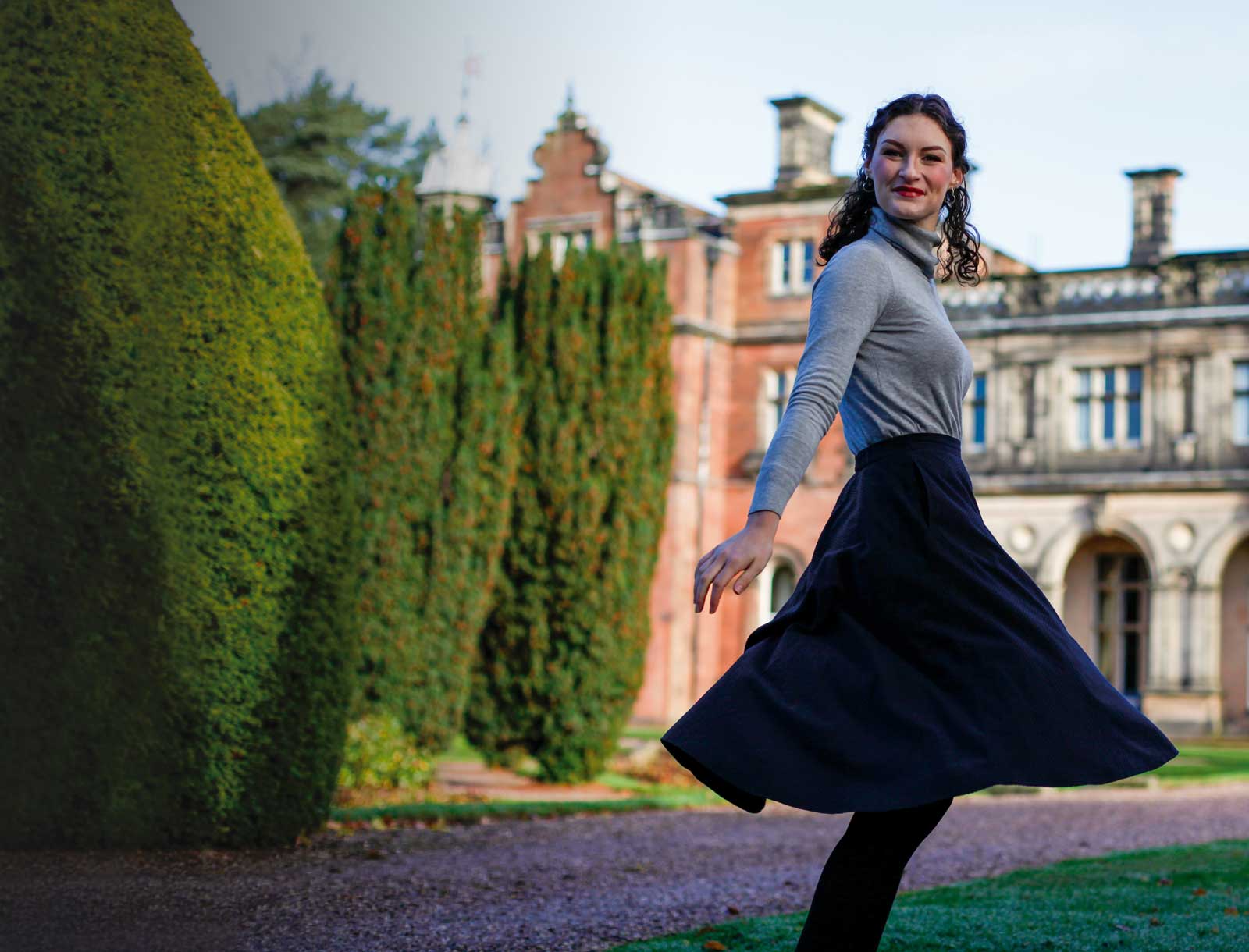 Stand out from the Crowd, student stands in front of Keele Hall looking happy and smiling into camera
